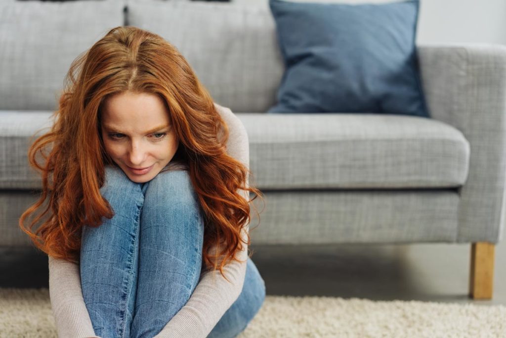 lagunashoresrecovery-7-Ways-to-Cope-with-Anxiety-Naturally-photo-of-Young-redhead-woman-sitting-on-the-carpet-thinking