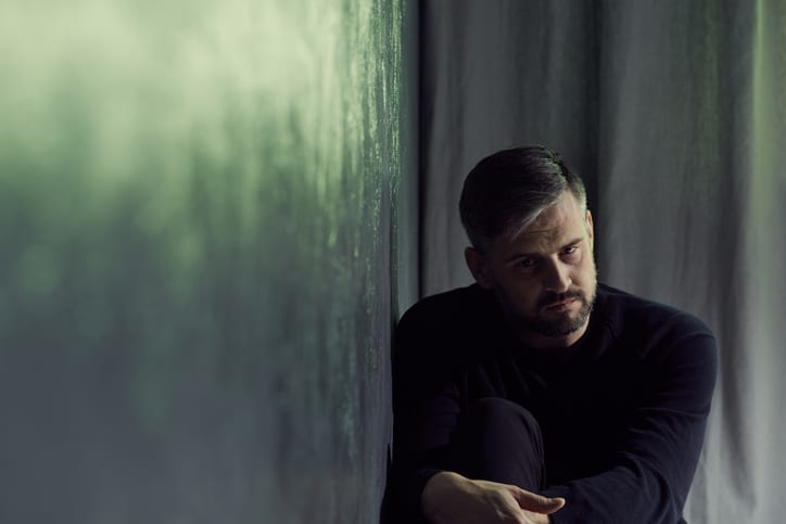 a man in a dark room next to a green wall