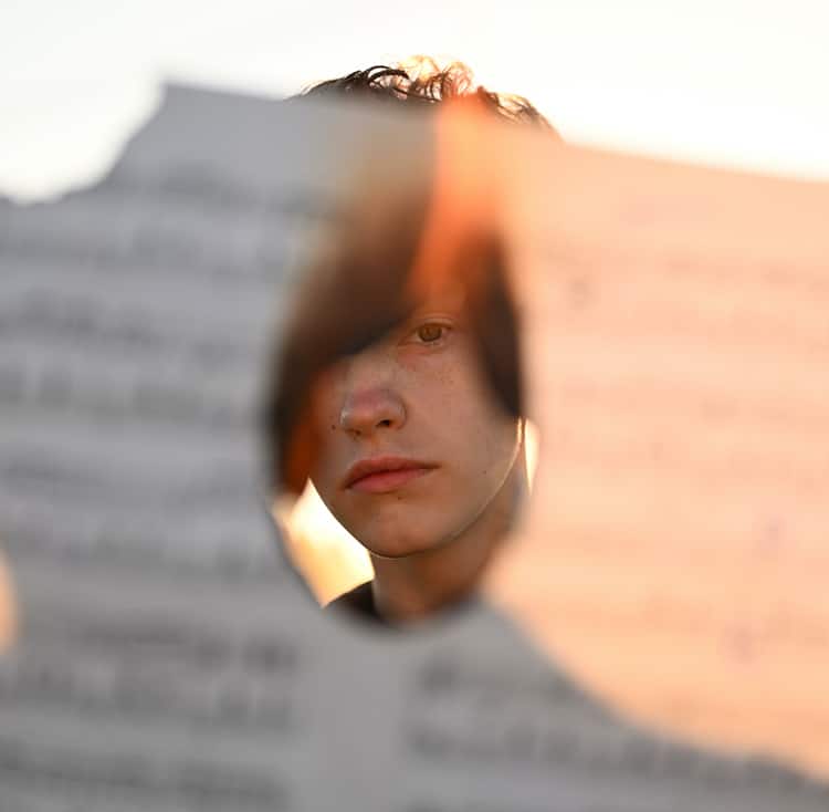 teenager looking through a hole from a burned paper