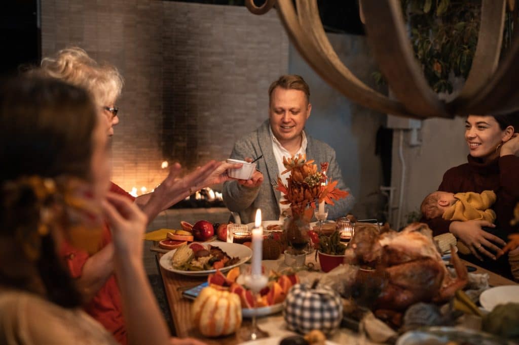 man in gray suit jacket holding white ceramic mug during family dinner